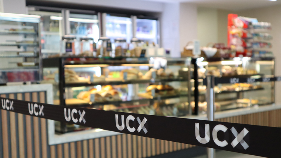 UCX tensile barrier in front of The Noshery food outlet fridges filled with a selection of sandwiches, wraps, salads.